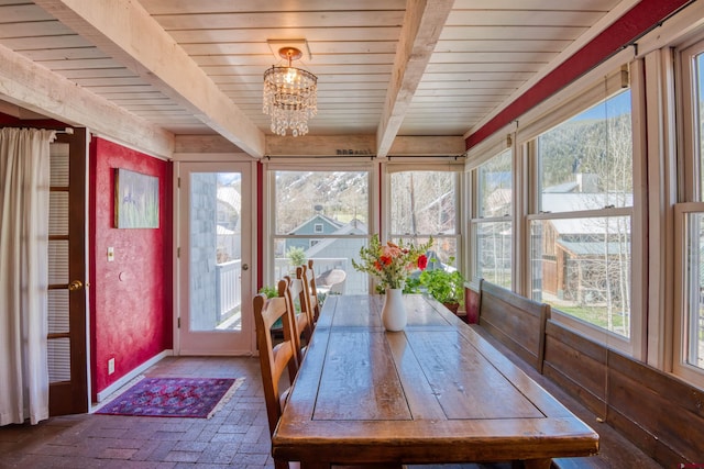 unfurnished sunroom featuring beamed ceiling, wooden ceiling, and a chandelier