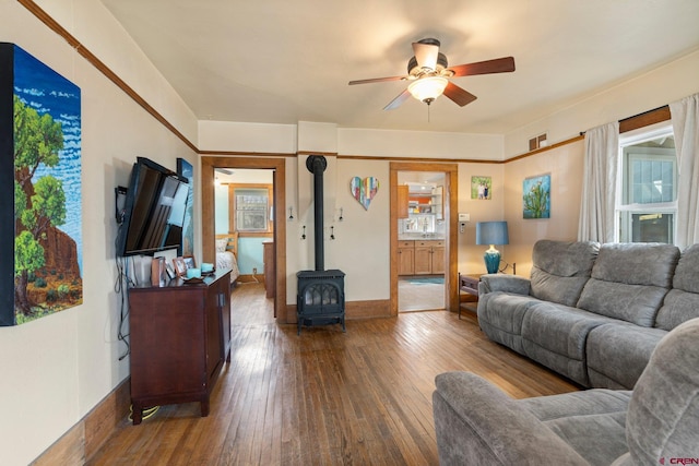 living room featuring hardwood / wood-style floors, ceiling fan, and a wood stove