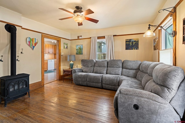 living room with dark hardwood / wood-style floors, a wood stove, and ceiling fan