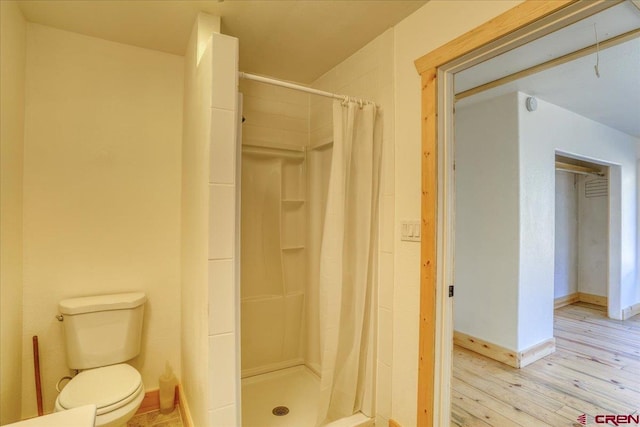 bathroom featuring a shower with curtain, hardwood / wood-style flooring, and toilet