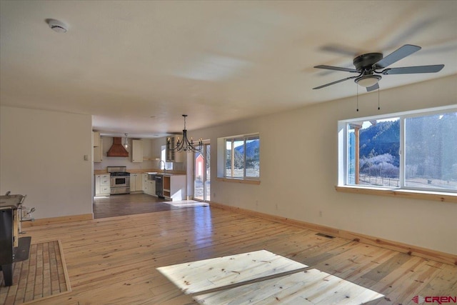 unfurnished living room featuring sink, ceiling fan with notable chandelier, and light wood-type flooring