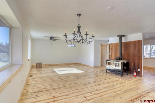 kitchen with decorative light fixtures, light hardwood / wood-style flooring, ceiling fan with notable chandelier, and a wood stove