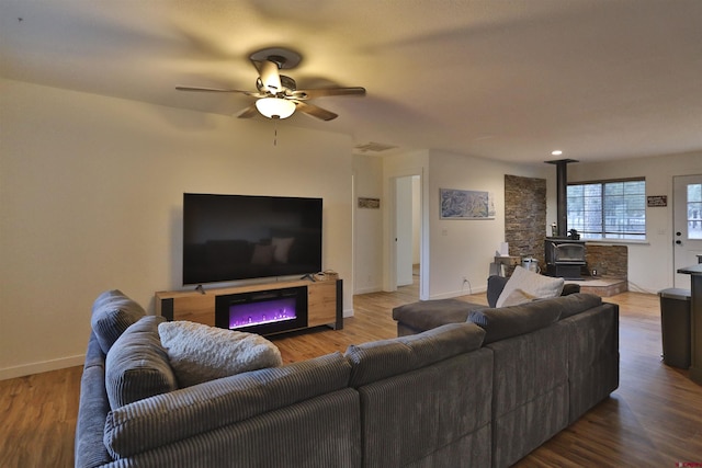 living room with hardwood / wood-style flooring, a wood stove, and ceiling fan