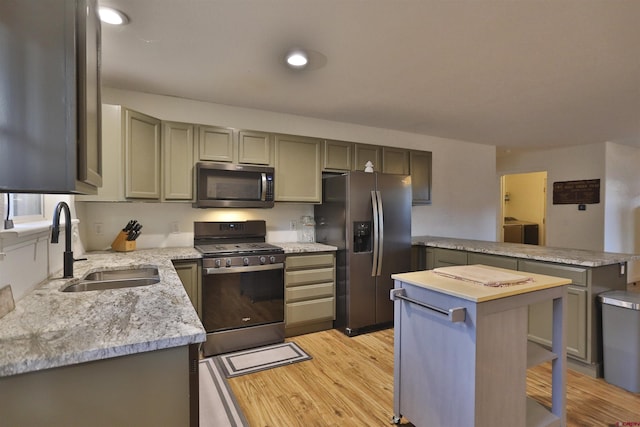 kitchen featuring sink, washer and dryer, light wood-type flooring, appliances with stainless steel finishes, and a kitchen island