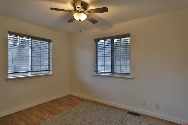 empty room with hardwood / wood-style floors, a healthy amount of sunlight, and ceiling fan