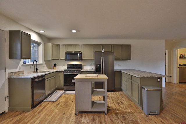 kitchen featuring washer / dryer, sink, a center island, light wood-type flooring, and appliances with stainless steel finishes