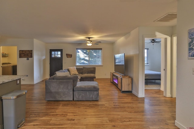 living room featuring ceiling fan, independent washer and dryer, and wood-type flooring