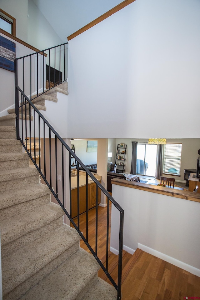 stairway with hardwood / wood-style flooring and high vaulted ceiling