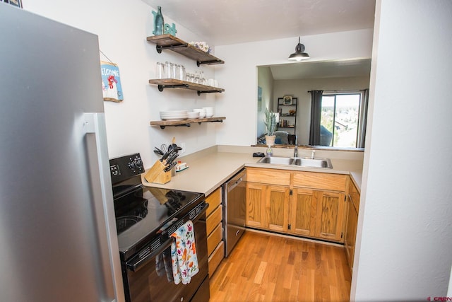 kitchen featuring stainless steel appliances, sink, pendant lighting, and light hardwood / wood-style floors