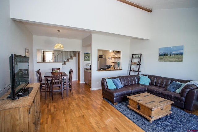 living room with a towering ceiling, hardwood / wood-style floors, and beam ceiling