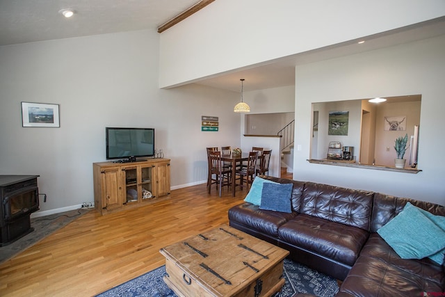 living room with hardwood / wood-style flooring, high vaulted ceiling, and a wood stove