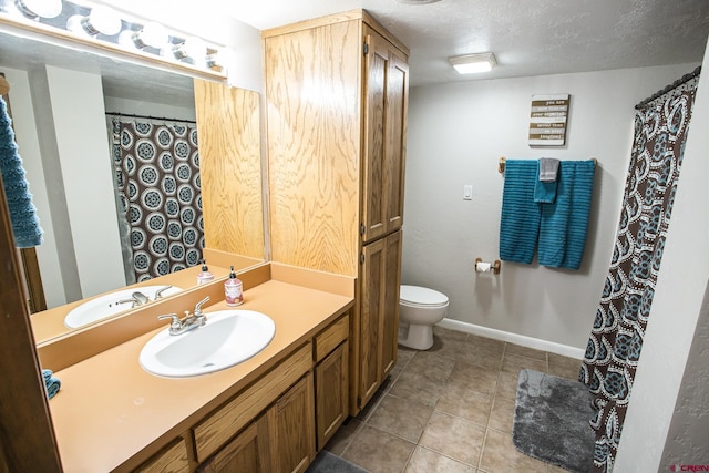 bathroom with tile patterned flooring, vanity, a textured ceiling, and toilet