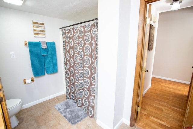 bathroom with walk in shower, tile patterned floors, a textured ceiling, and toilet