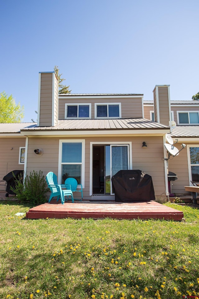 rear view of house featuring a lawn and a deck