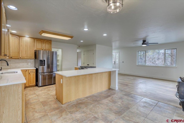 kitchen with sink, stainless steel fridge, a center island, tasteful backsplash, and light brown cabinets