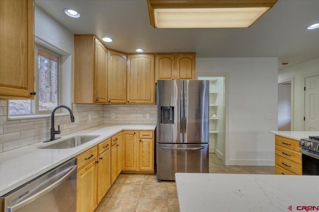 kitchen featuring appliances with stainless steel finishes, sink, decorative backsplash, light tile patterned floors, and light brown cabinets