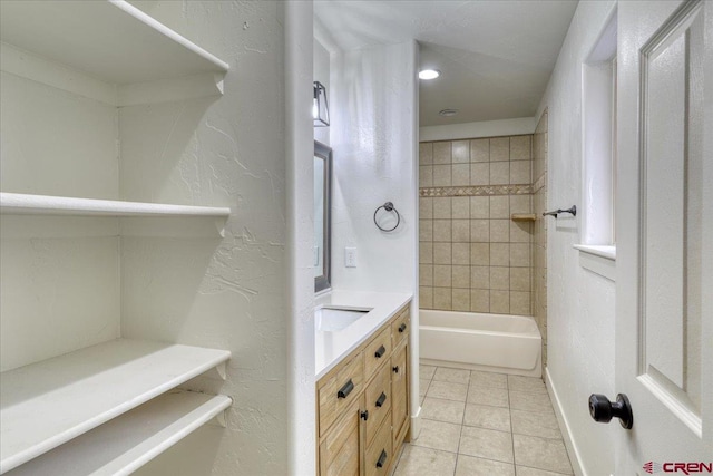 bathroom with tile patterned flooring, vanity, and tiled shower / bath