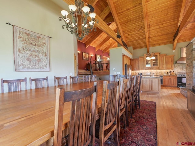 dining room featuring beamed ceiling, light wood-type flooring, wood ceiling, and an inviting chandelier