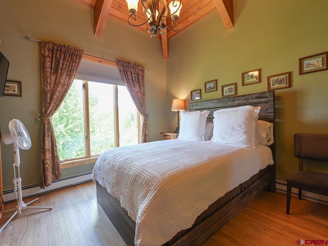 bedroom with a baseboard heating unit, a notable chandelier, lofted ceiling with beams, and hardwood / wood-style floors