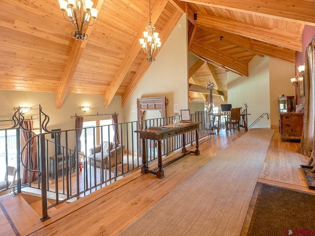 corridor featuring wood-type flooring, plenty of natural light, high vaulted ceiling, and an inviting chandelier