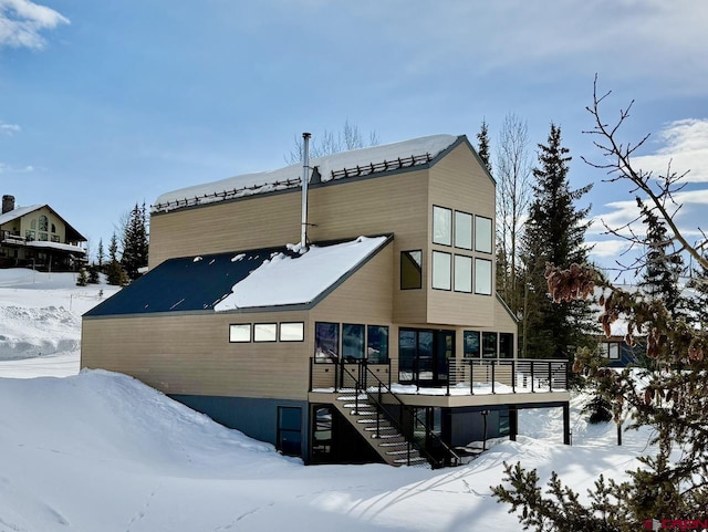 snow covered house featuring a wooden deck