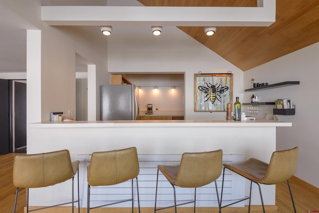 bar featuring vaulted ceiling, wood ceiling, stainless steel refrigerator, and light hardwood / wood-style floors