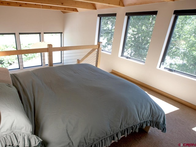 carpeted bedroom featuring multiple windows and beamed ceiling