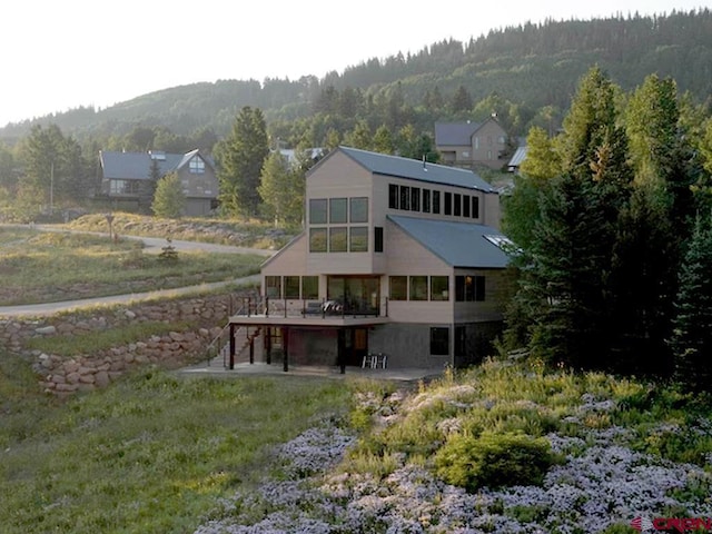 rear view of property with a deck with mountain view and a sunroom