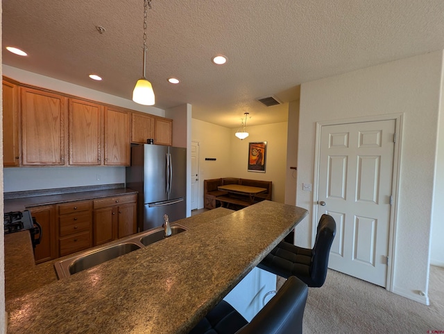 kitchen with pendant lighting, a breakfast bar area, stainless steel refrigerator, light carpet, and kitchen peninsula