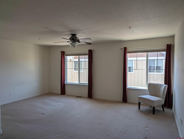 spare room with ceiling fan, light carpet, and a textured ceiling