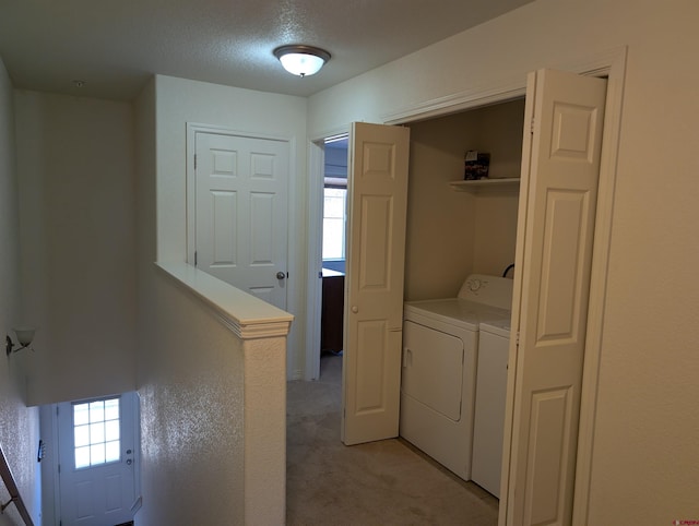 laundry area with washer and dryer, light carpet, and a textured ceiling