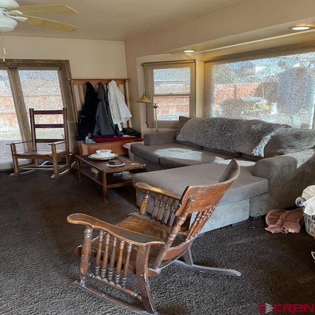 sunroom featuring ceiling fan and dark colored carpet