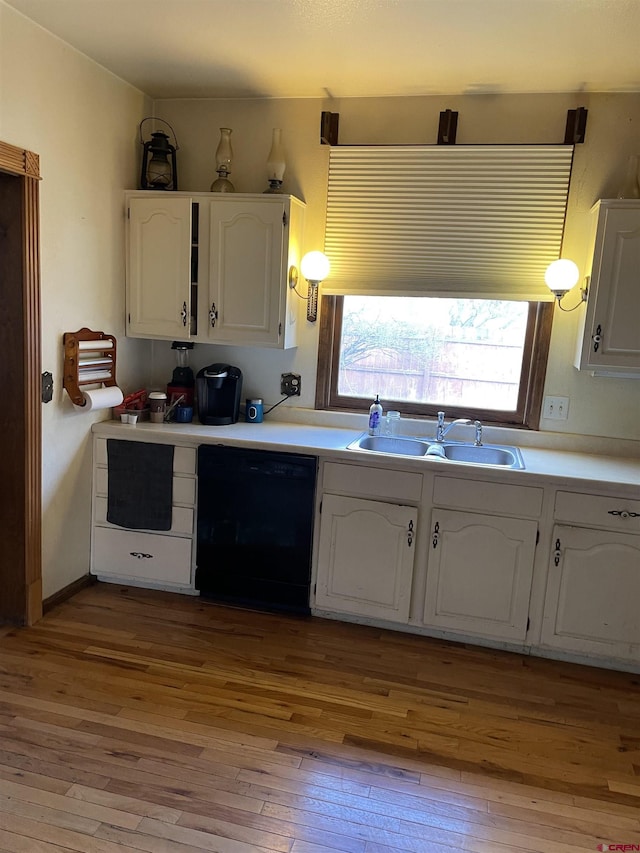 kitchen featuring white cabinetry, black dishwasher, sink, and light wood-type flooring