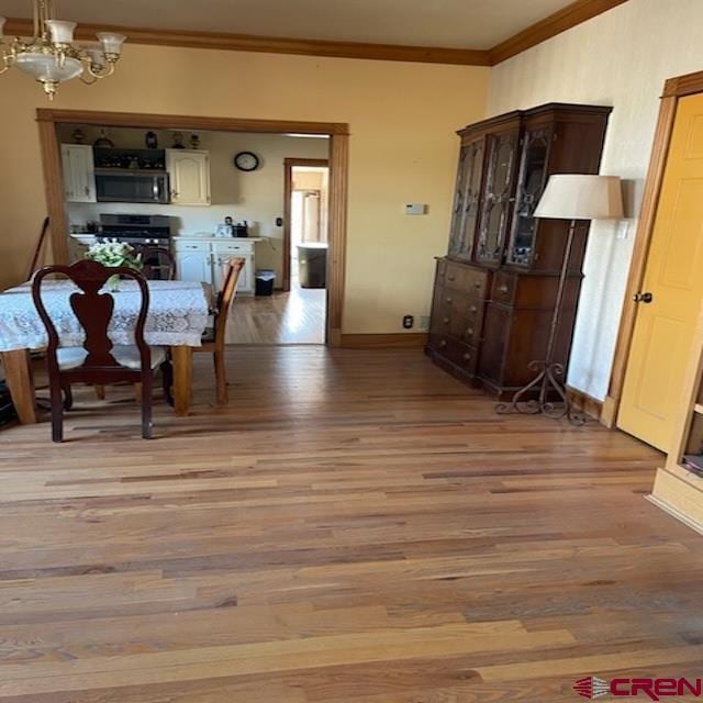 dining area with crown molding, a chandelier, and light wood-type flooring