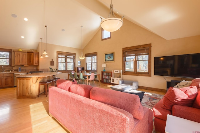 living room featuring beamed ceiling, sink, high vaulted ceiling, and light hardwood / wood-style flooring