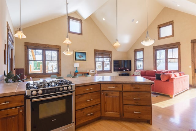 kitchen with pendant lighting, stainless steel gas range, and light wood-type flooring