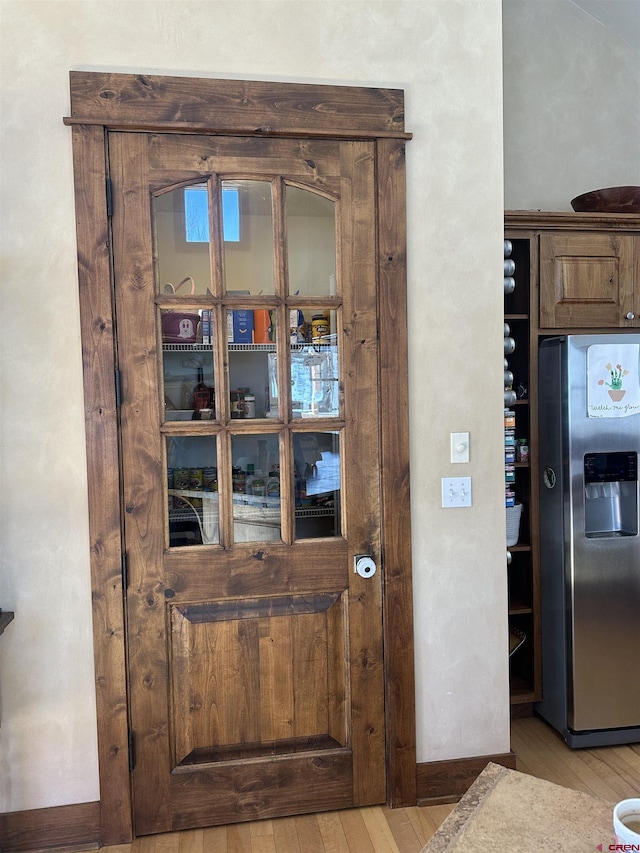 interior details featuring light hardwood / wood-style floors and stainless steel fridge with ice dispenser