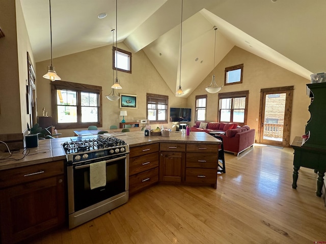 kitchen featuring pendant lighting, a healthy amount of sunlight, light hardwood / wood-style flooring, and stainless steel gas stove