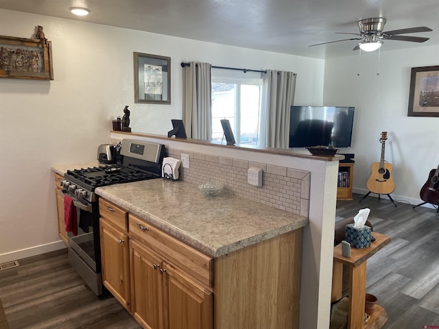 kitchen featuring dark wood-type flooring, ceiling fan, stainless steel range with gas stovetop, and decorative backsplash