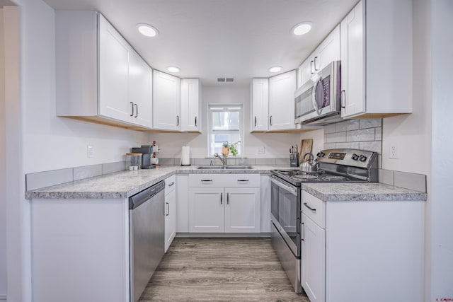 kitchen with sink, light hardwood / wood-style flooring, stainless steel appliances, and white cabinets