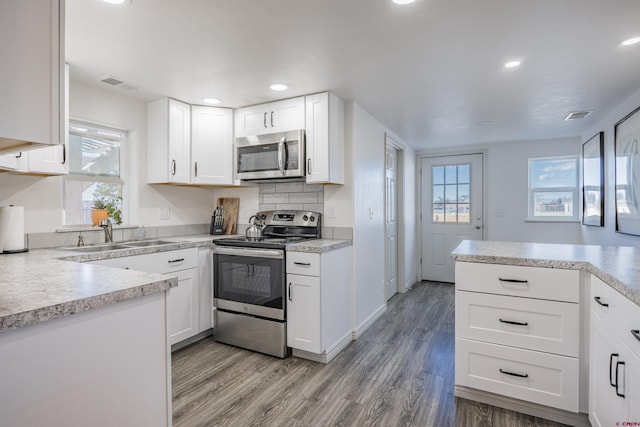 kitchen featuring stainless steel appliances, sink, white cabinets, and light hardwood / wood-style flooring