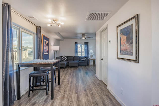 dining space with ceiling fan with notable chandelier and hardwood / wood-style floors