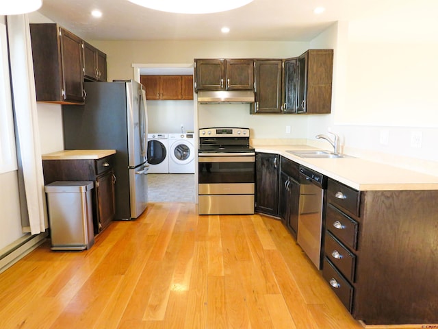 kitchen featuring sink, appliances with stainless steel finishes, dark brown cabinets, separate washer and dryer, and light wood-type flooring