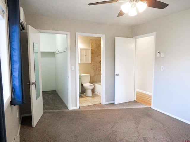 unfurnished bedroom featuring ensuite bath, a spacious closet, light carpet, a closet, and ceiling fan