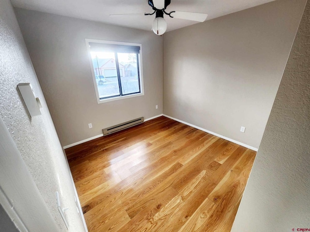 unfurnished room featuring hardwood / wood-style flooring, a baseboard radiator, and ceiling fan