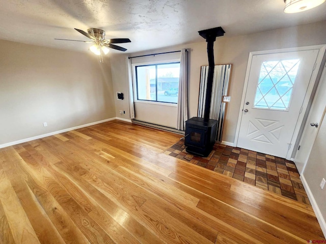 entrance foyer featuring hardwood / wood-style flooring, a wood stove, and ceiling fan