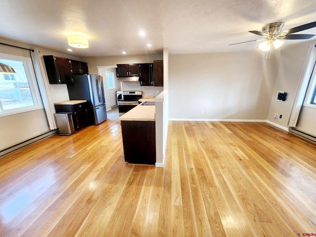 kitchen with dark brown cabinets, light wood-type flooring, baseboard heating, ceiling fan, and stainless steel appliances