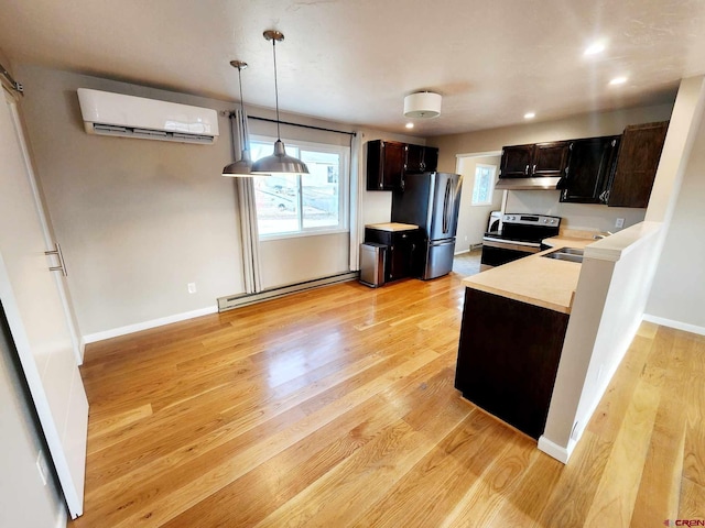 kitchen featuring pendant lighting, baseboard heating, appliances with stainless steel finishes, a wall mounted AC, and light hardwood / wood-style floors