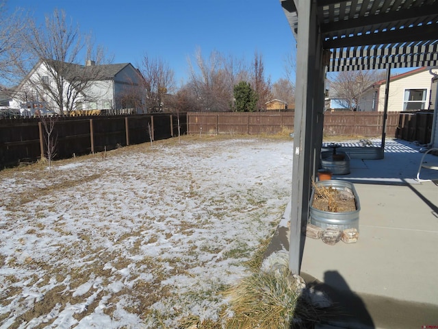 yard covered in snow with a patio area and a pergola