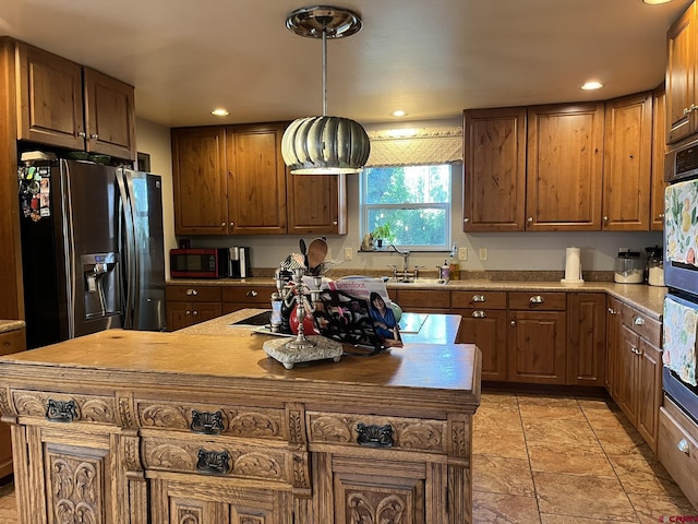 kitchen with a kitchen island, pendant lighting, double oven, sink, and stainless steel fridge with ice dispenser